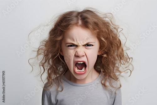 Angry little girl child shouting or screaming. Facial emotions. Empty space studio shot isolated on white background