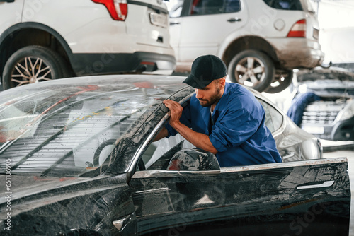 Dirty car is moved by auto mechanic that is in garage. Repair service