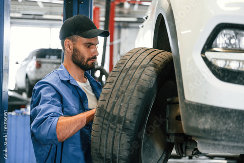 Setting up new wheel. Auto mechanic working in garage. Repair service