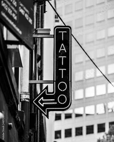 A tattoo studio sign in black and white in a downtown city setting
