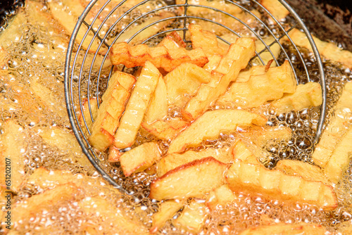 French fries cooking. Close-up of frying french fries in a deep fryer in hot oil