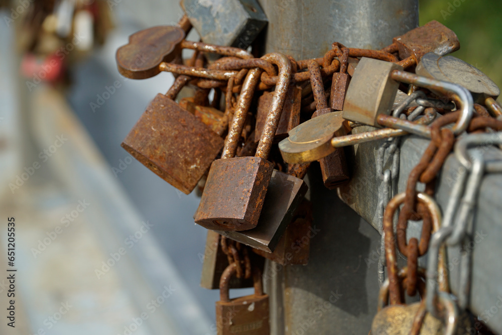 Many rusty padlocks closed on bridge fence - love concept