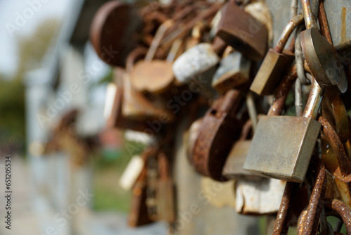 Many rusty padlocks closed on bridge fence - love concept