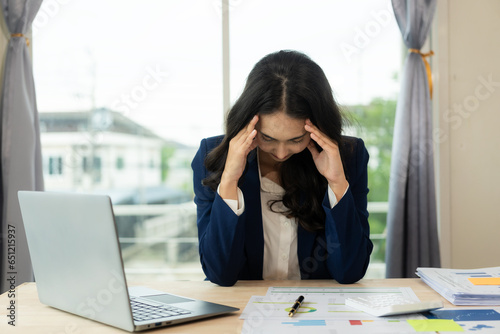 Tired young freelance worker rubbing eyes while sitting in front of laptop computer and office syndrome concept, young Asian woman tired, overworked, feeling headache, having vision problems