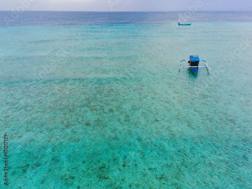 Drone photo of traditional fishermen boats in the blue and clear waters of Pulau Tabuhan, Banyuwangi, Indonesia