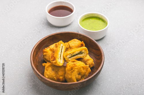 Paneer Pakoda with sweet and tangy chutney on a wooden plate, served hot