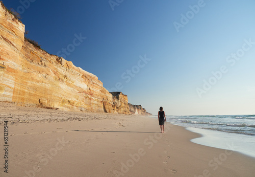 Eine Frau vor Klippen am Strand in Leiria, Portugal