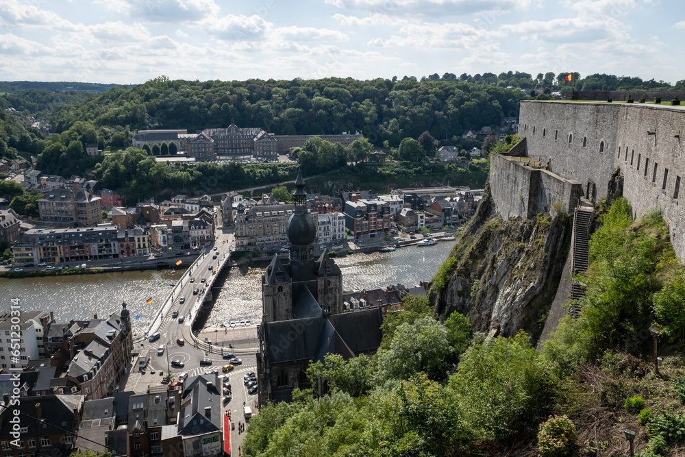 Tourist attraction museum Citadelle de Dinant in Belgium mountaintop fortress in historic Ardennes. Medieval fortified barracks with national flag overlooks city and river on sunny summer day