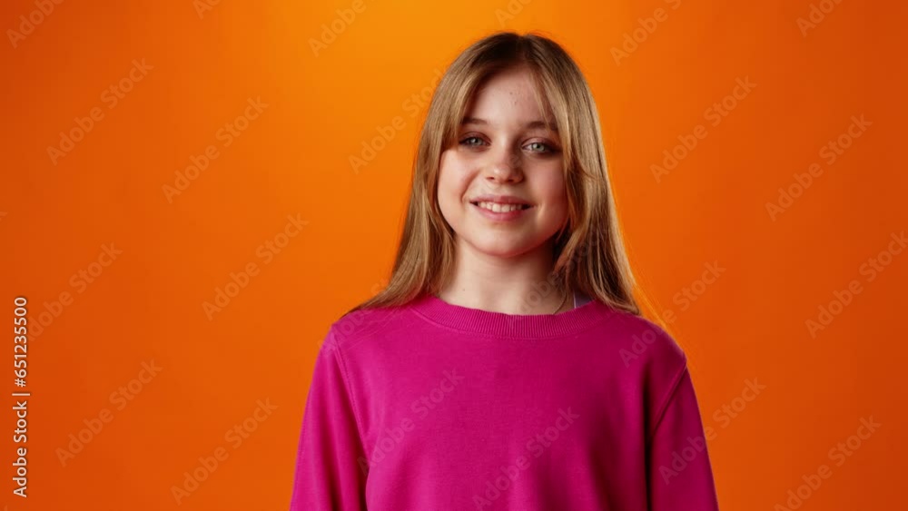 Friendly nice teen girl smiling against yellow background in studio