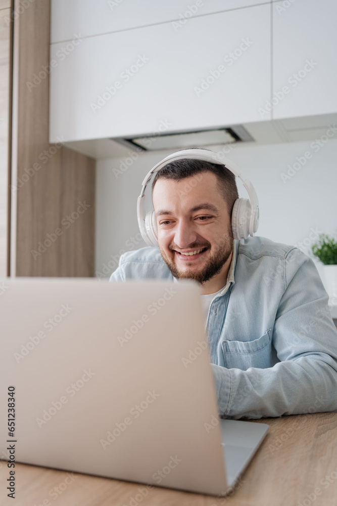 Young man with laptop and headphones indoors at home, studying, freelance working Young man with laptop and headphones indoors at home, studying, freelance working