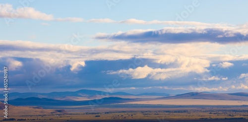 Panoramic landscape with Khakassia steppe under sky with heavy clouds at early autumn day in Siberia  Russia. Cloud shadows lie on the ground