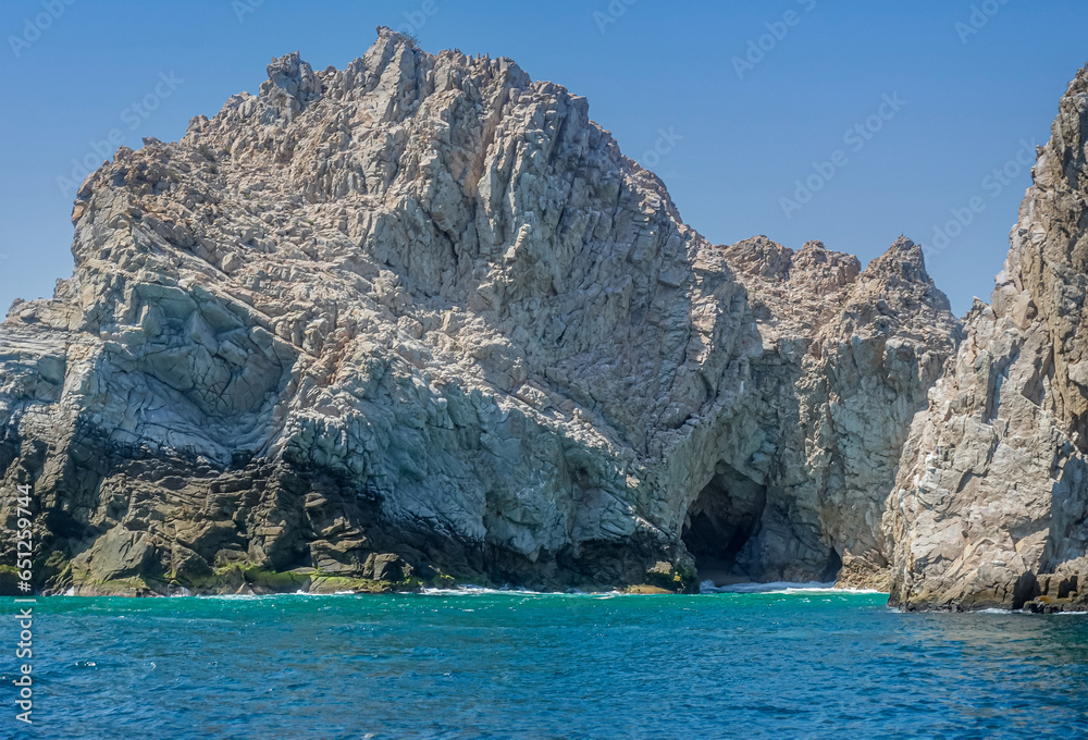 Mexico, Cabo San Lucas - July 16, 2023: Closeup, cave, on Reserva de lobos Marinos, set in gray-beige rocky cliffs descending into greenish ocean water