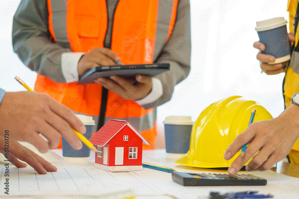 Construction engineer. businessman engineer Meet in the office to discuss building design for the client. 3rd male engineer designs house structure on table in office Construction engineer. businessman engineer Meet in the office to discuss building design for the client. 3rd male engineer designs house structure on table in office
