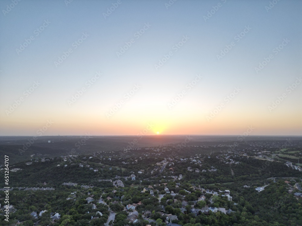 Obraz premium Sunset over the city and hill country. Clear blue skies. Orange sun. Vistas and panoramas.