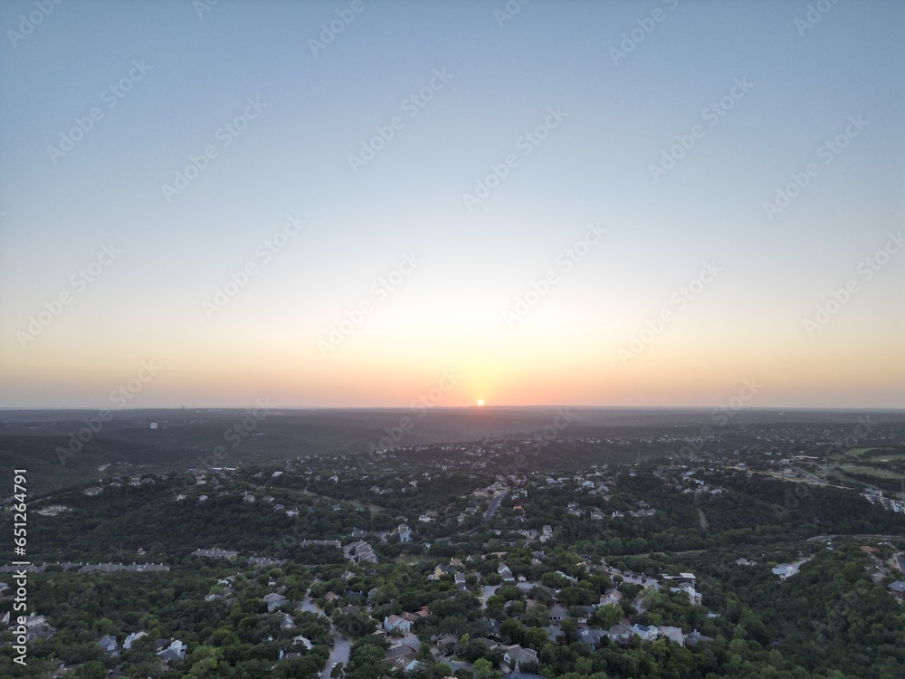 Sunset over the city and hill country. 
Clear blue skies. Orange sun. Vistas and panoramas.