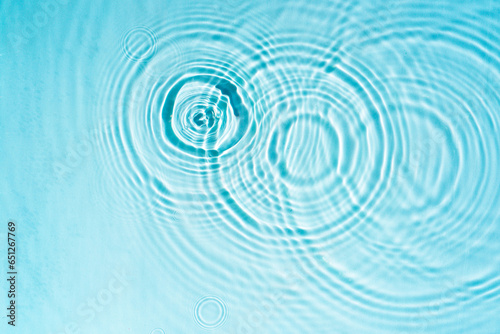 Circles and waves on blue water in sunlight