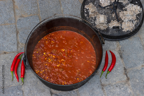 Top view of chili con carne cooked in the dutch oven with red hot peppers.  photo