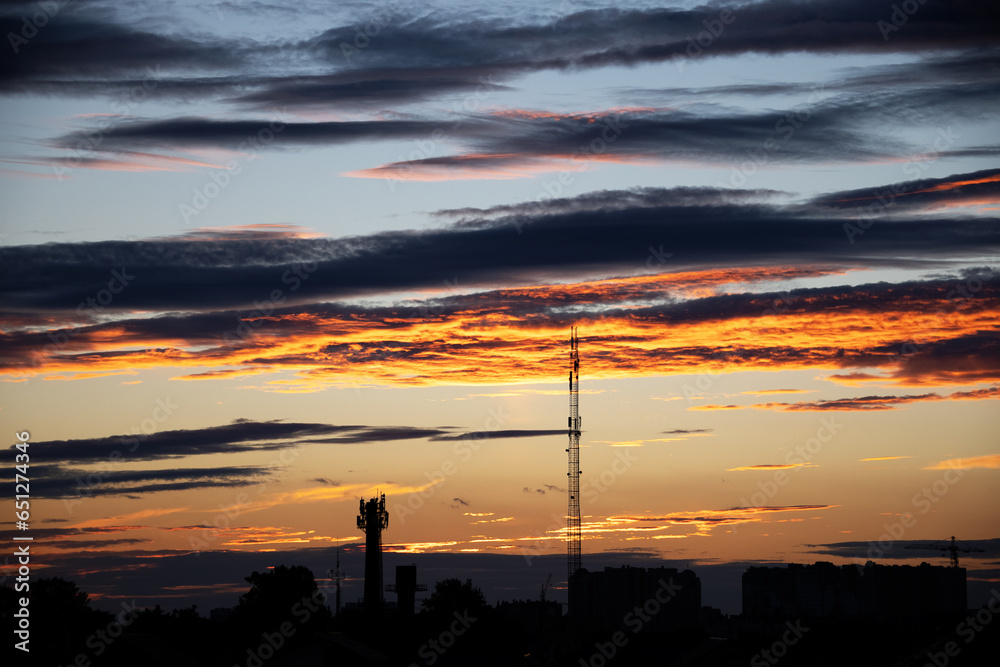 Dark, clear silhouettes of roofs of houses with chimneys and pipes in rays of setting sun. Sunset in city. Silhouette City landscape in backlight of sunset. Landscape Sky.