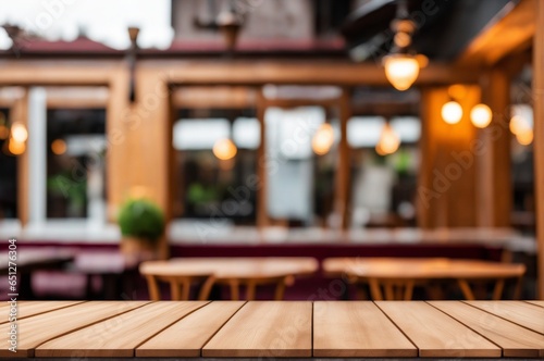 Clear wooden table with soft-focus lights in a blurred background of an outdoor cafe. High-quality image.