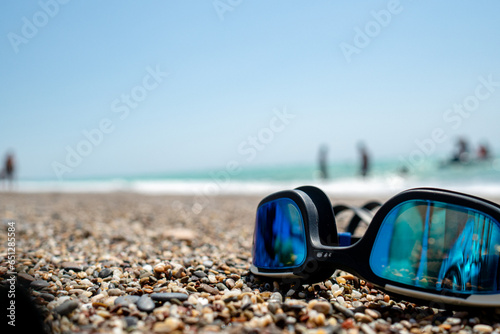 swimming glasses laying on a blanket during hot summer day with blurred background, holiday and travel concept
