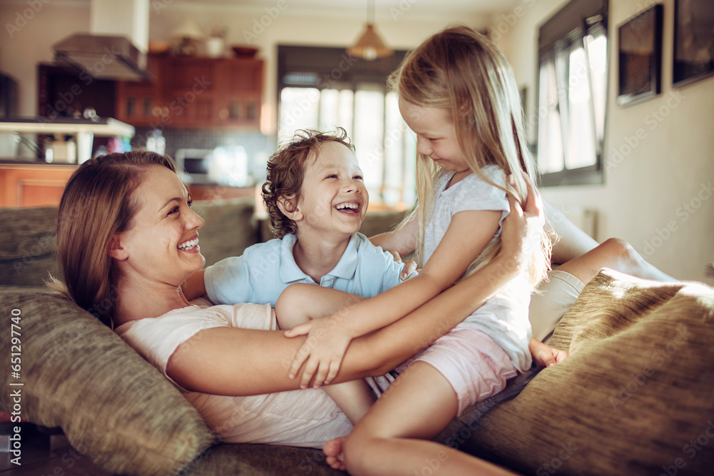 Young mother playing with her children on the couch in the living room at home Young mother playing with her children on the couch in the living room at home