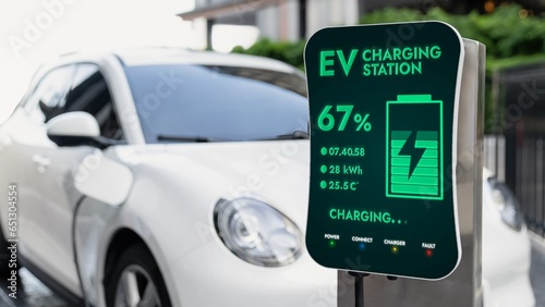 Futuristic clean energy utilization of smart EV charging station in residential area recharging electric car's battery. Technological advancement of high-tech EV car in modern city lifestyle. Peruse