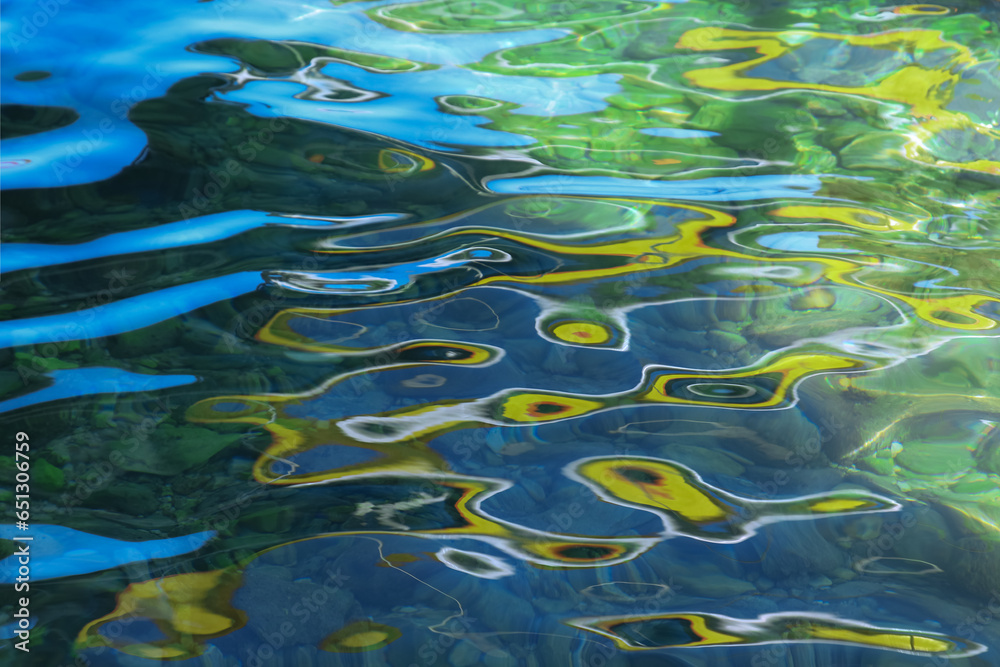 Blue water with yellow green ripples on the surface. Defocused blurred colorful transparent water surface texture. Abstract surface. Water waves with shining pattern texture background. Sea Blue water with yellow green ripples on the surface. Defocused blurred colorful transparent water surface texture. Abstract surface. Water waves with shining pattern texture background. Sea