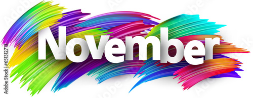 November paper word sign with colorful spectrum paint brush strokes over white.