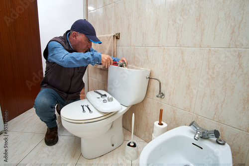 Bild auf Leinwand Plumber repairing a toilet cistern