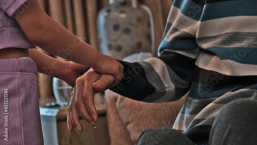 The little girl helping the old man. The grandchild helping his grandfather up. Granddaughter holding her grandfather's hand.