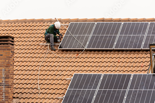 Técnico instalando placas solares en un chalet.	