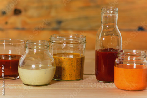 Handmade spicy sauces in glass jars on a colored wooden base - Salsas picantes hechas artesanalmente en frascos de vidrio sobre fondo de madera de colores