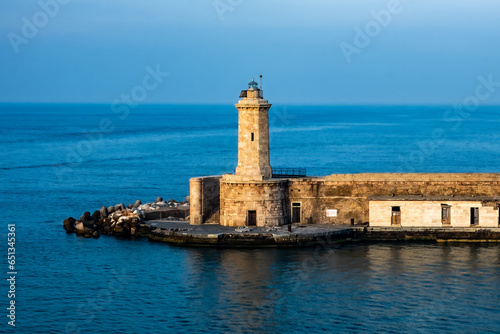 One of the Livorno  Italy lighthouses in the golden glow of the morning sun. Still water and blue sky contrast with the warm sunlight.