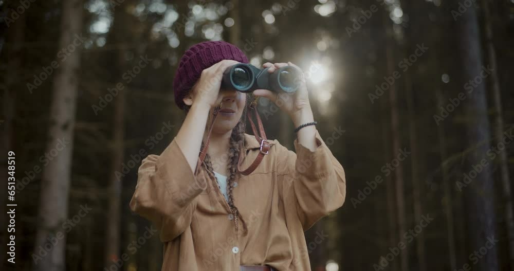 Female explorer with binoculars in forest