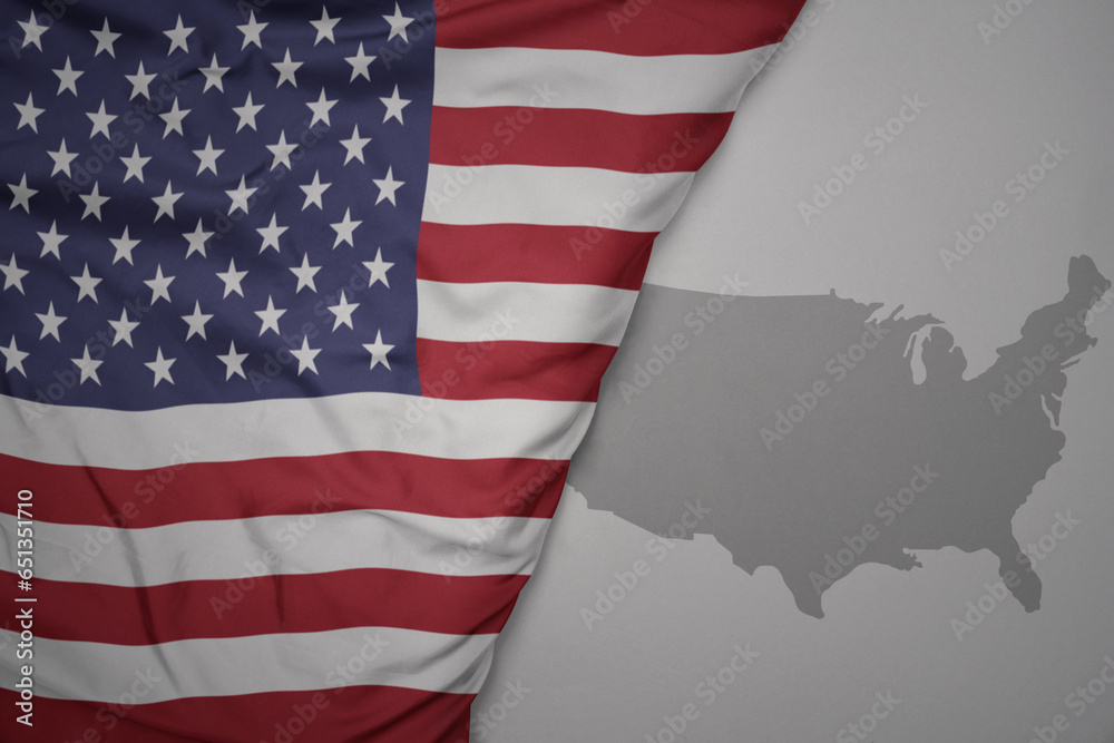 Obraz premium big waving national colorful flag and map of united states of america on the gray background.