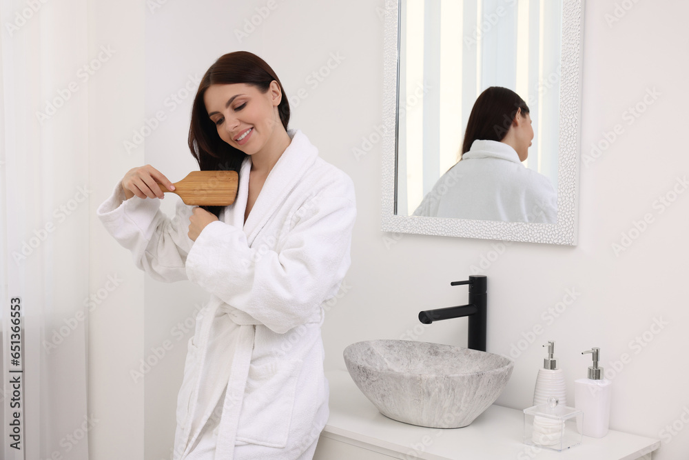Fototapeta premium Beautiful woman brushing her hair in bathroom
