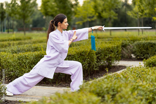 Caucasian man working out with Tai Chi sword in the morning at the park photo