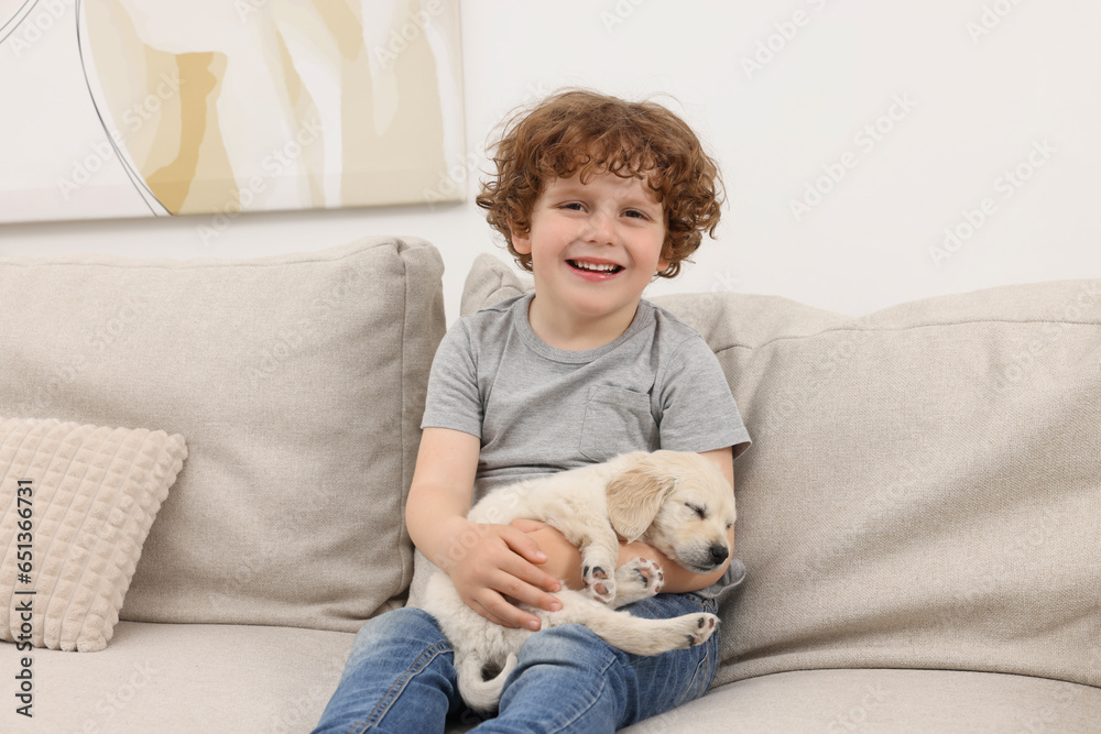 Little boy hugging cute puppy on couch indoors Little boy hugging cute puppy on couch indoors