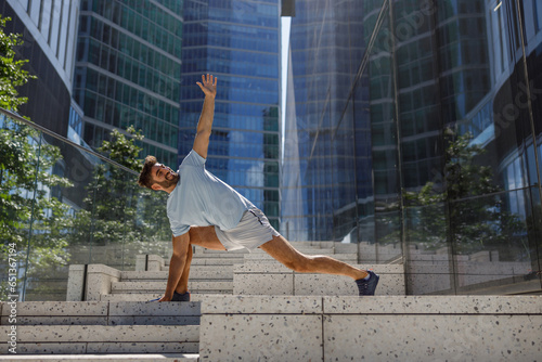 Healthy sporty man doing stretch on modern city skyscrapers background. Healthy lifestyle concept