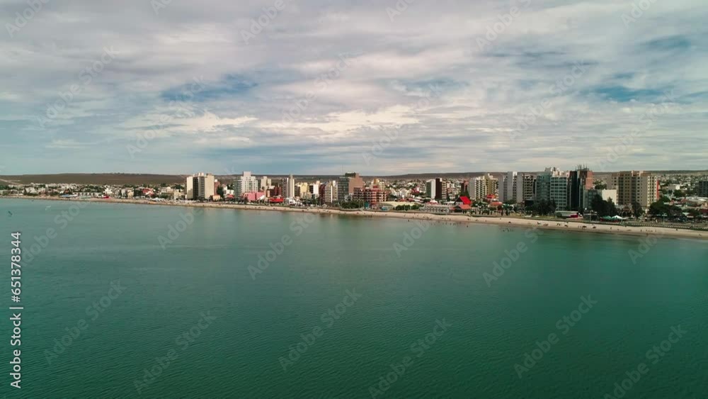 Aerial Forward Descending Towards Beach By Buildings In City Against Cloudy Sky - Puerto Madryn, Argentina Aerial Forward Descending Towards Beach By Buildings In City Against Cloudy Sky - Puerto Madryn, Argentina