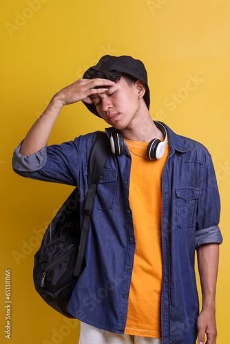 Young Asian male student in casual stylr touching his head feeling tired photo