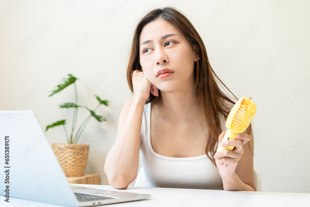 Suffering summer heat wave stroke, hot weather, tired asian young woman, girl refreshing by using portable fan with blowing when female working on table at home, ventilation when temperature high Suffering summer heat wave stroke, hot weather, tired asian young woman, girl refreshing by using portable fan with blowing when female working on table at home, ventilation when temperature high