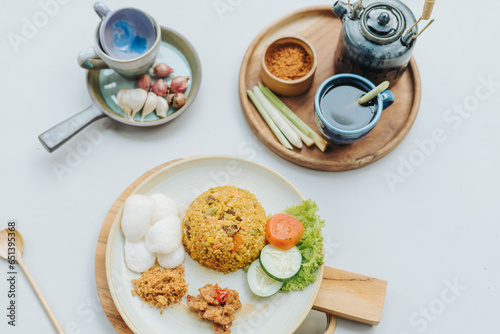 Indonesian food nasi goreng or fried rice served with abon chicken floss, kerupuk crackers, and vegetables photo