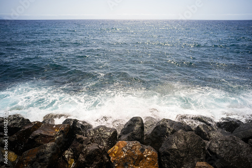 Splashes of water on the rocks of the ocean shore on a sunny day.