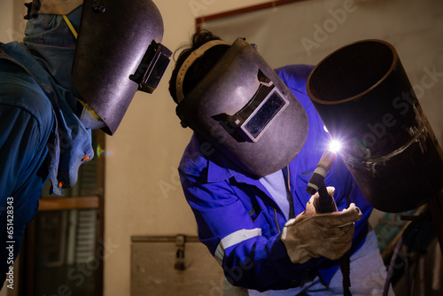 Bild auf Leinwand A man is training to be a welder and another person is in charge of the examination