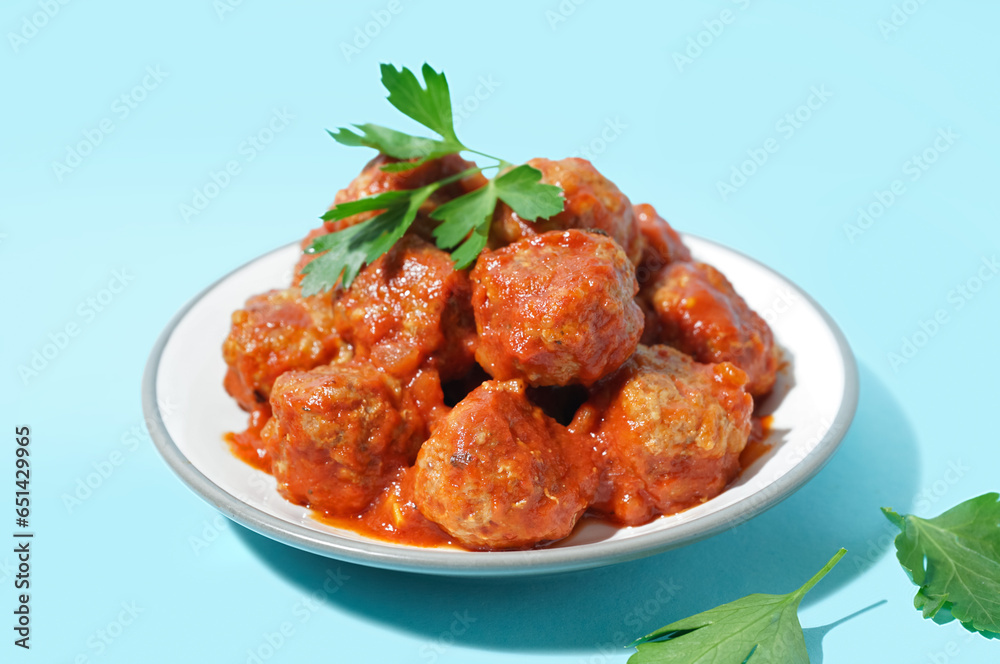 Plate of tasty meat balls with sauce on blue background