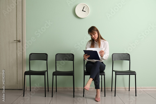 Female applicant with clipboard waiting for job interview in room