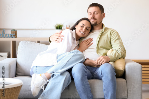 Happy young couple hugging on sofa at home