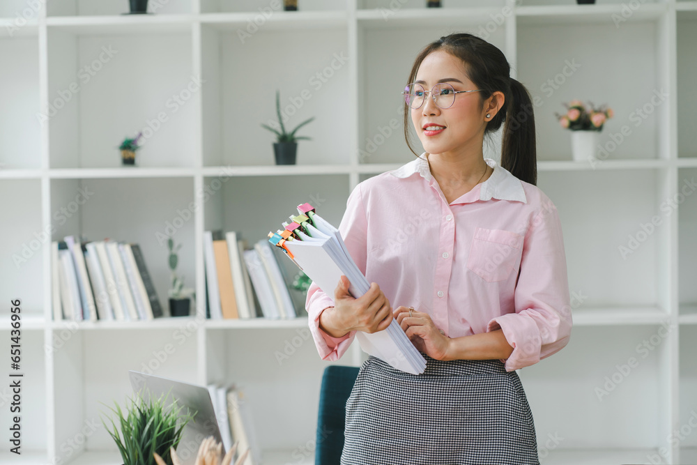 Asian businesswoman or accountant using a calculator, graphs, and charts to analyze market data, balance sheets, accounts, and net profits. Asian businesswoman or accountant using a calculator, graphs, and charts to analyze market data, balance sheets, accounts, and net profits.