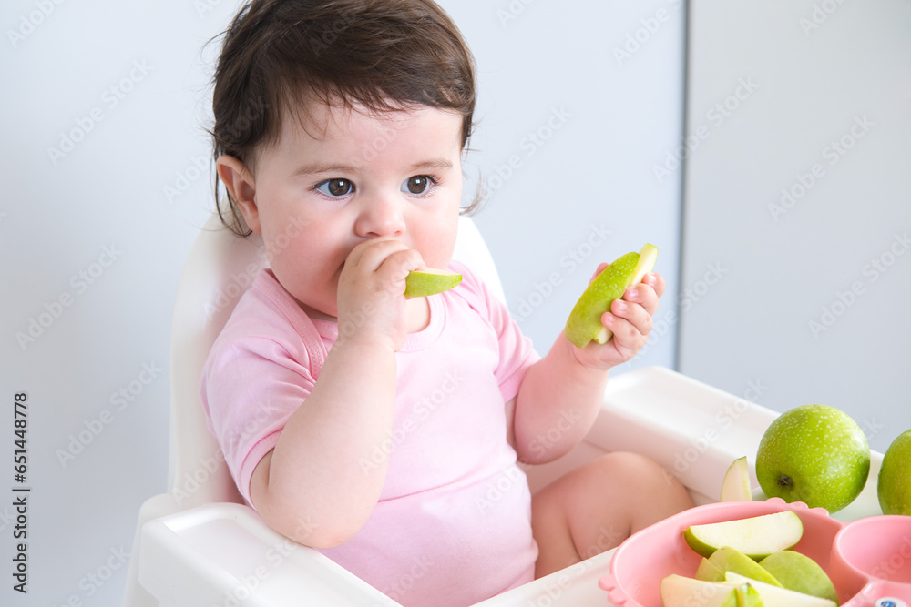 baby eating apple sitting in a high chair. weaning baby eating apple sitting in a high chair. weaning